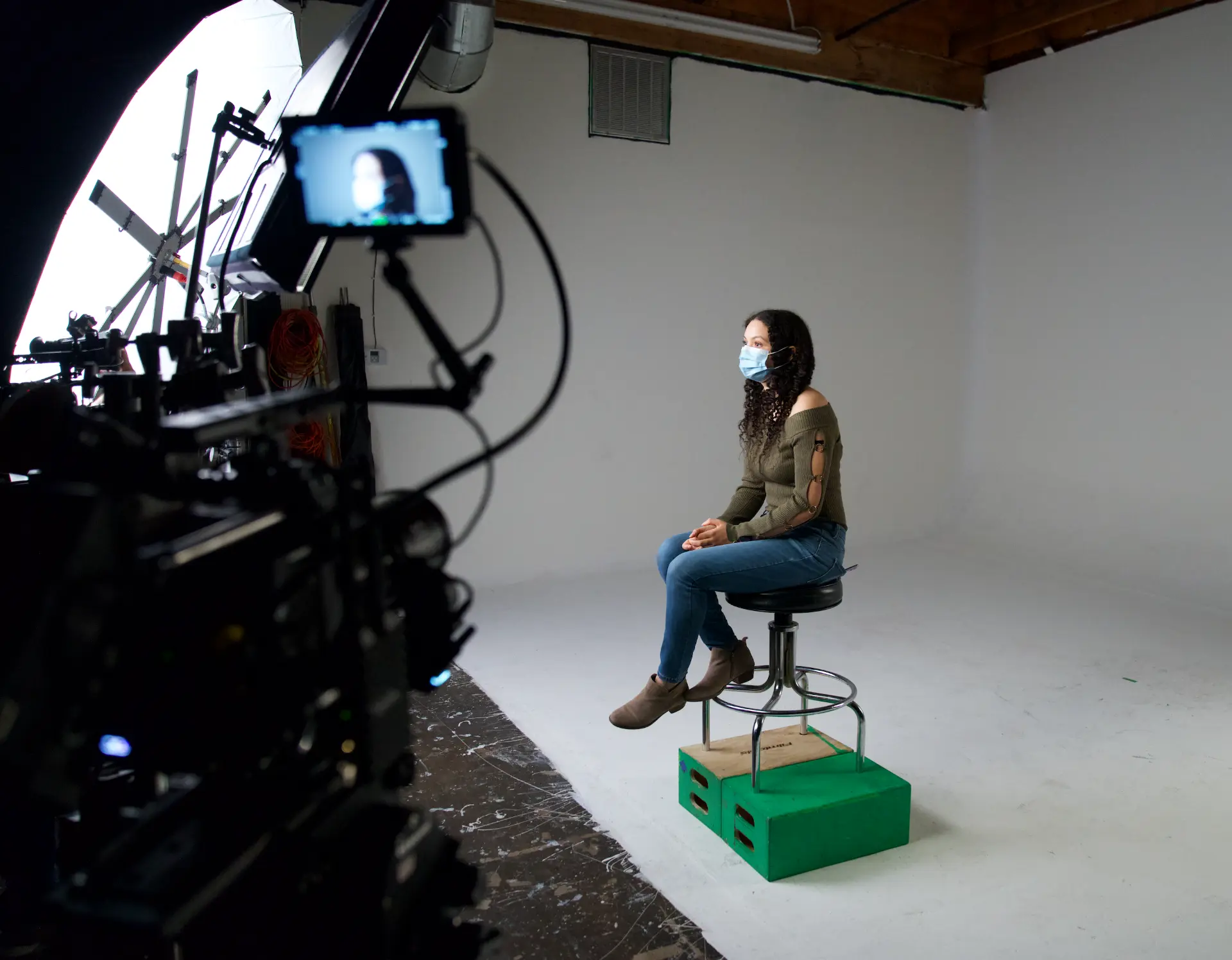 Seated interview subject on the white cyc, monitor in frame during a Los Angeles shoot produced by E'Ian West of Montage Media Production Company
