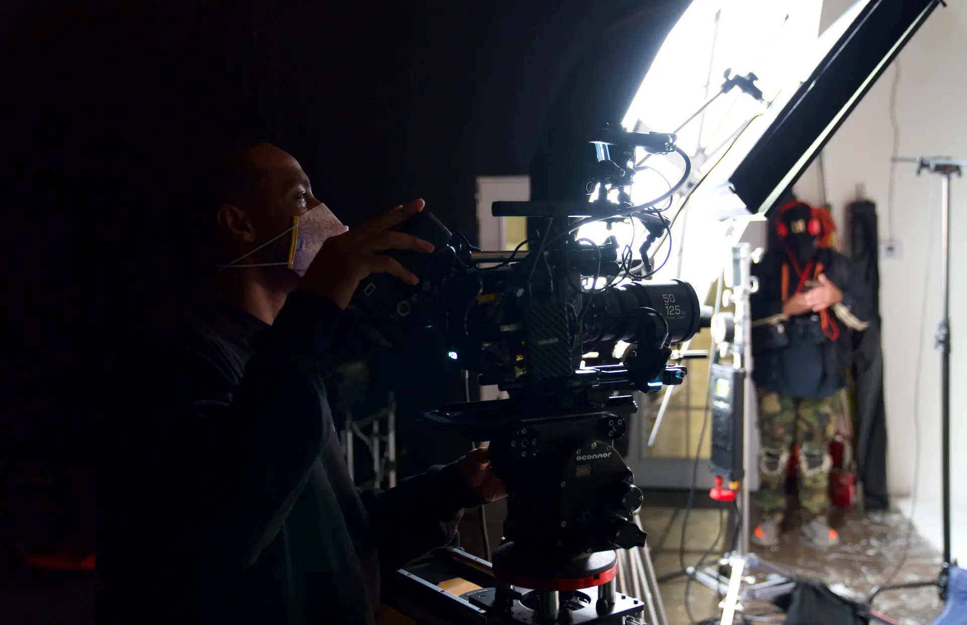 Montage Media Production Company crew, operator lining up the A camera beside a large soft source, on a production overseen by E'Ian West